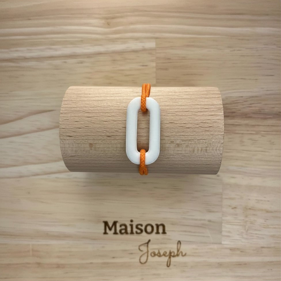 Maison Joseph white ceramic link bracelet on adjustable orange sport cord. Modern, minimalist design.